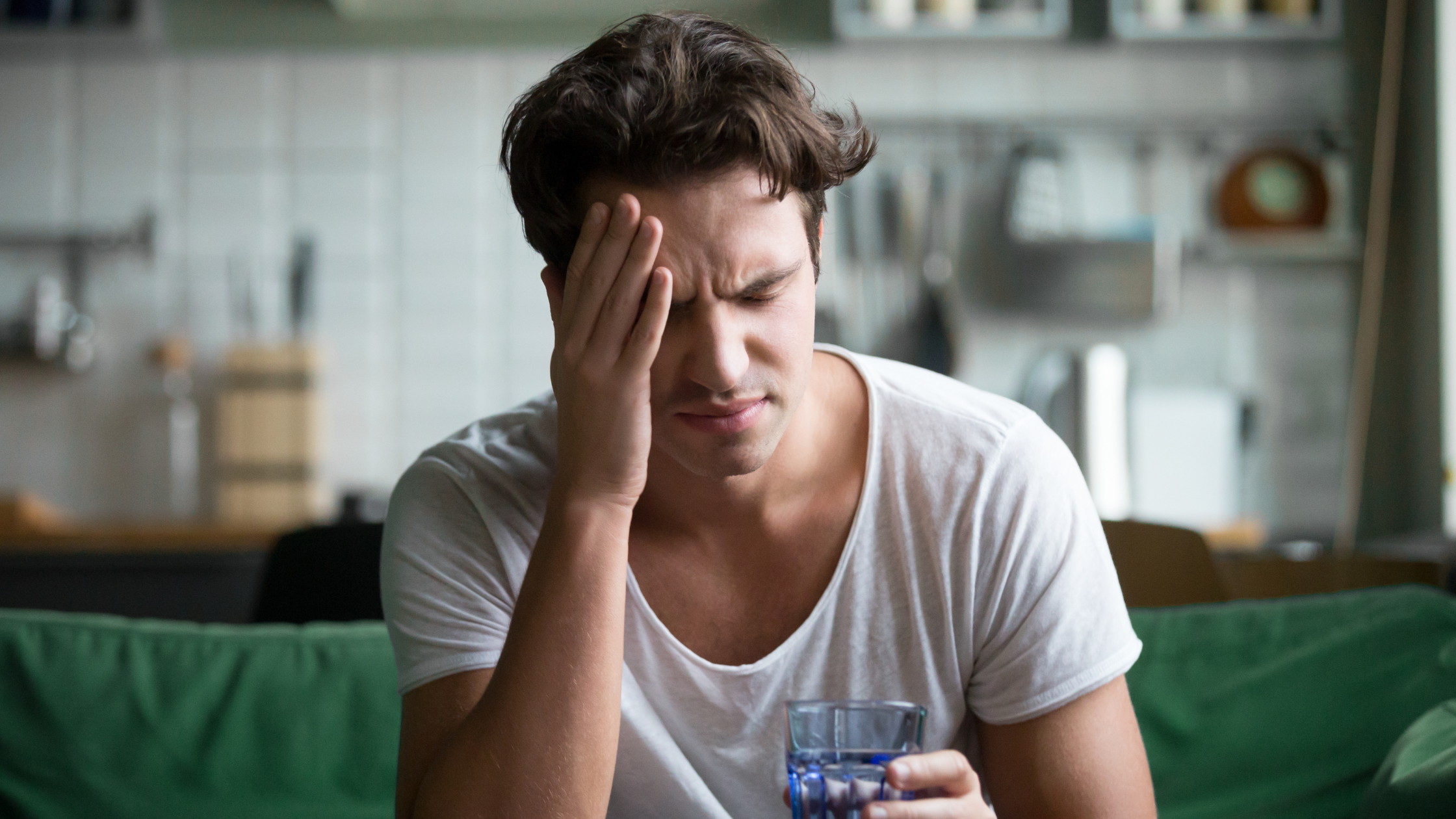 Man with headache sitting on edge of bed, suffering from hangover. IV therapy as a hangover cure is discussed in this blog post by Cutler Integrative Medicine in Bloomfield Hills, Michigan.